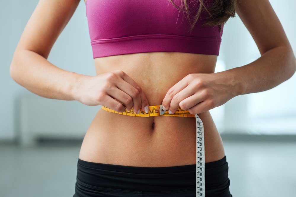 Slim woman measuring her thin waist
